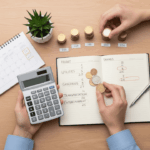 Hands organizing coins and a calculator on a desk with a budget notebook, representing the process of creating a personal budget and managing finances.